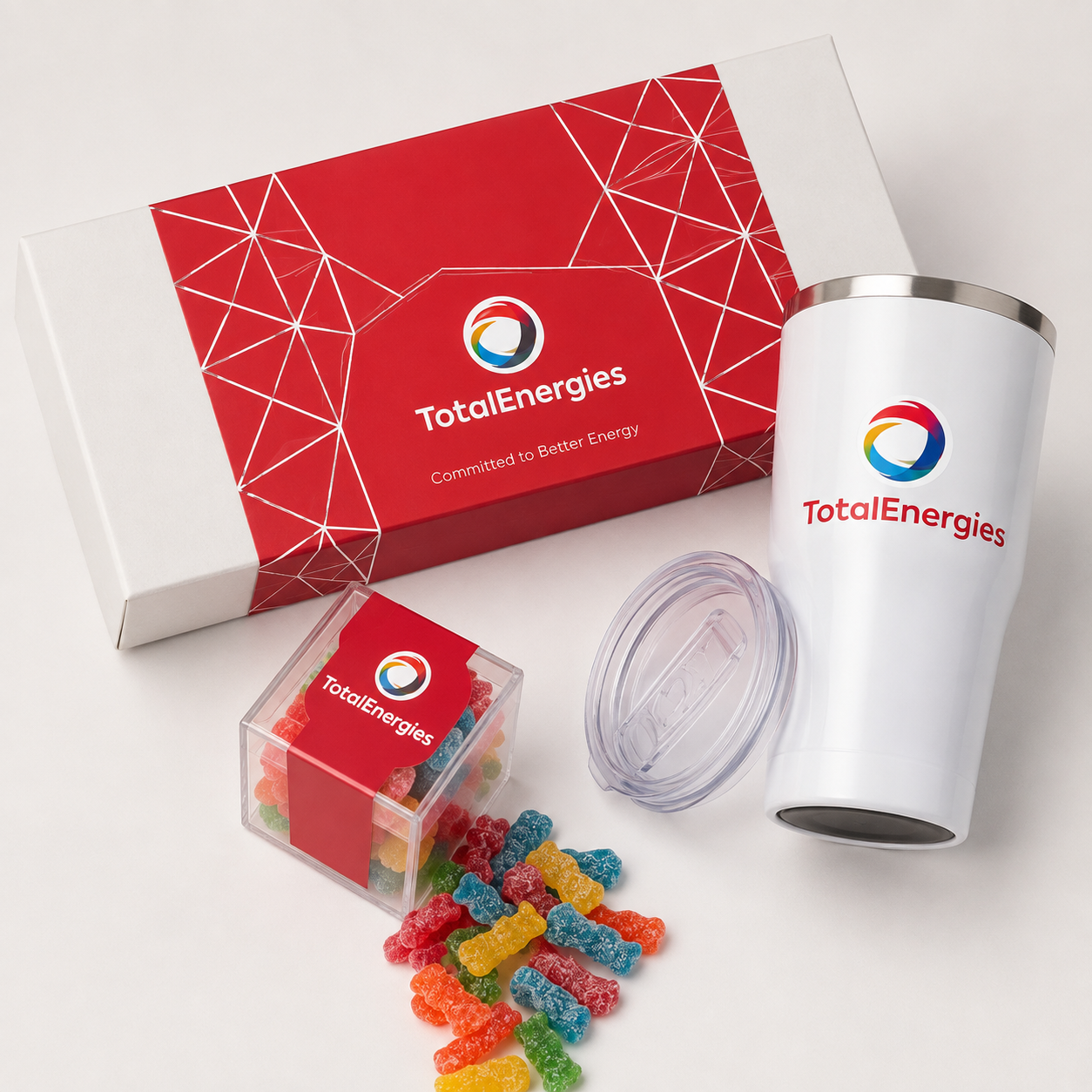 White insulated tumbler and a box of sour gummy candy in a red branded gift box